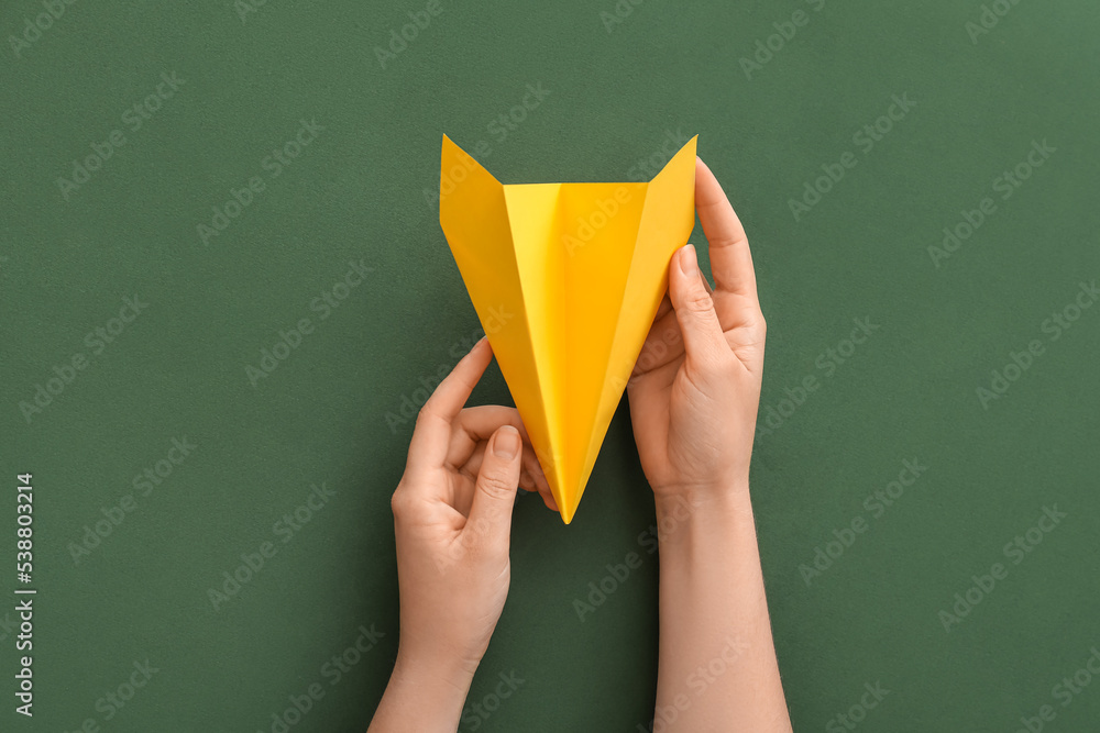 Woman with yellow paper plane on green background