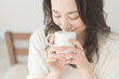 © lielos - 朝、温かい飲み物を飲む女性
