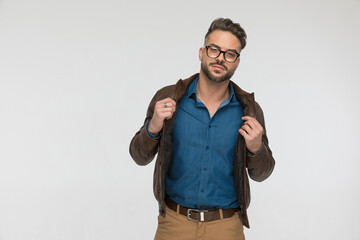 Wall Mural - confident casual man with blue denim shirt and leather jacket posing