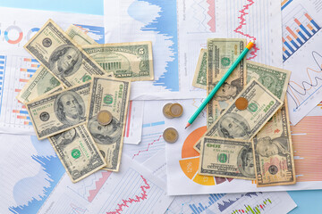 Wall Mural - Dollar banknotes with coins, pencil and diagrams on blue background. Exchange rate concept