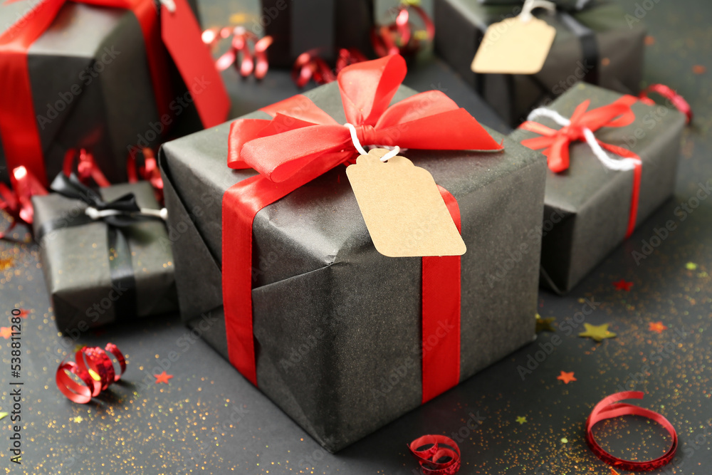 Gift box with price tag on dark background, closeup. Black Friday sale