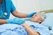 © manassanant - Doctor holding hands Asian elderly woman patient, help and care in hospital.
