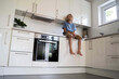 © Westend61 - Boy sitting on kitchen counter at home