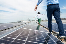 Businesswoman And Businessman Walking Amidst Solar Panels On Rooftop