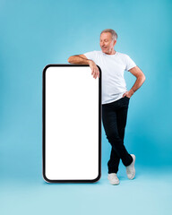 Wall Mural - Senior man leaning on big white empty smartphone screen