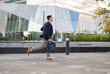 © Westend61 - Businessman with bag running in front of building