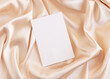 © katrinshine - Blank card on beige silky fabric drapery top view, greeting or wedding mockup