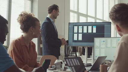 Diverse team of male and female programmers having meeting in office. Man in formalwear making presentation to colleagues