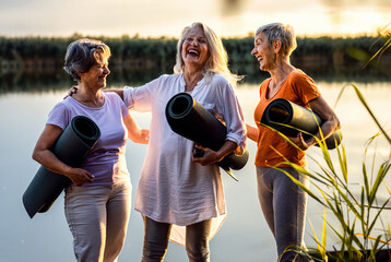 Wall Mural - Group of senior woman with yoga mats talking after exercise.