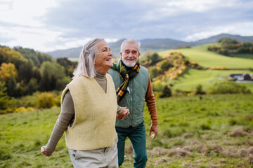 Wall Mural - Happy senior couple walking in autumn meadow.