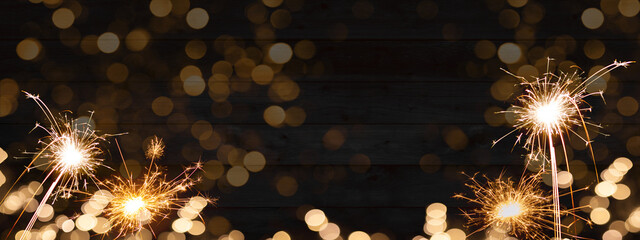 Sylvester, New Year's Eve 2025 Party, New year, Fireworks, Firework celebration background banner panorama long- Sparklers and bokeh lights on rustic black wooden wall texture.