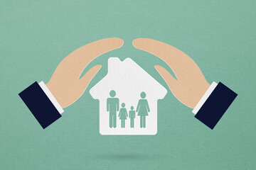 businessman's hand cover white house paper cut with family icon inside on grunge green background