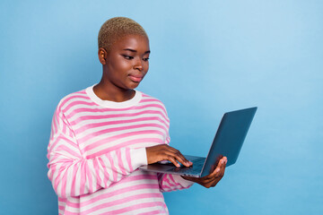 Photo of young attractive concentrated girl hold typing laptop search google isolated on blue color background