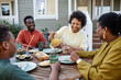 © Seventyfour - Portrait of smiling black woman pouring lemonade drinks to glass during family gathering outdoors