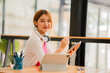 © ArLawKa - Asian female students studying online e-learning with tablet sitting at a desk and holding a pen distance learning concept at coffee shop