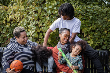 Wall Mural - African American family relaxing on bench in park in fall 