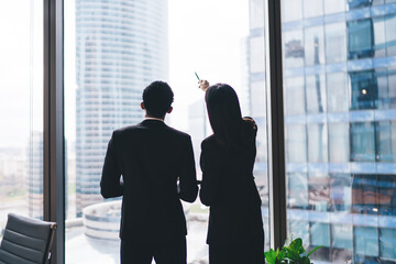 Wall Mural - Faceless colleagues standing near glass wall in office