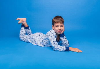 a little boy is sitting in pajamas on a blue background. the concept of healthy sleep. pajamas made of natural material for children