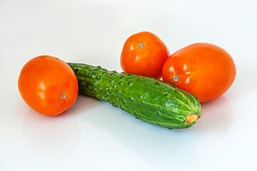 Wall Mural - fresh juicy cucumber and tomatoes for salad on white glass surface