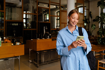 Wall Mural - Young white woman wearing shirt smiling while using cellphone