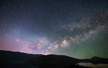 Wall Mural - Beautiful night landscape. Mountains and small under bright milky way galaxy. Starry night.