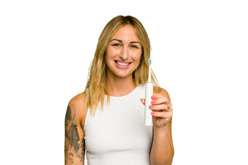 Wall Mural - Young caucasian woman holding electric toothbrush isolated on green chroma background happy, smiling and cheerful.