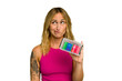 Young caucasian woman holding battery box isolated on green chroma background confused, feels doubtful and unsure.