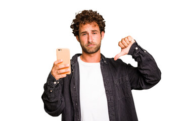 Young caucasian man using mobile phone isolated showing a dislike gesture, thumbs down. Disagreement concept.