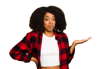 Wall Mural - Young African American woman isolated showing a copy space on a palm and holding another hand on waist.