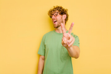 young caucasian man isolated on yellow background showing number two with fingers.