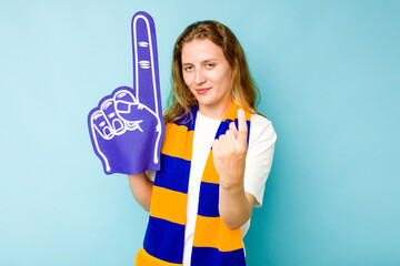 Young caucasian sports fan woman isolated on blue background pointing with finger at you as if inviting come closer.