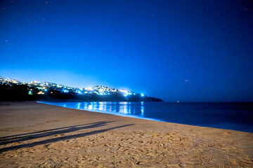 Wall Mural - beach at night with city in the background, bright lights, shadows on the sand, pie de la cuesta acapulco, guerrero mexico 