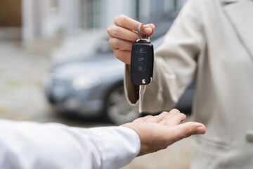 transportation rental automotive business concept. Close up hands of rental auto agent giving car remote key to client to travel sightseeing.