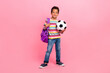 © deagreez - Full size photo of nice cheerful positive boy wear striped shirt jeans bag pack holding football ball isolated on pink color background