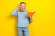 Photo of cheerful positive retired guy wear blue sweater spectacles reading book empty space isolated yellow color background