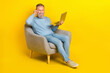 © deagreez - Full length photo of cheerful person sit chair hand touch glasses use netbook isolated on yellow color background