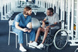 © Seventyfour - Young doctor in uniform discussing rehabilitation with patient while he sitting in wheelchair in gym
