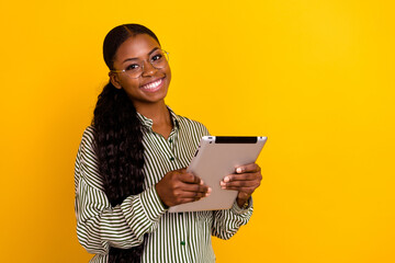 Wall Mural - Photo of confident satisfied person hold tablet toothy smile look camera isolated on yellow color background