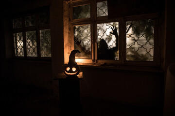 Scary Halloween pumpkin in the mystical house window at night or halloween pumpkin in night on room with blue window. Symbol of halloween in window. Selective focus