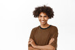 © Cookie Studio - Portrait of handsome hispanic male model with curly hair, smiling and looking happy, posing in casual pose with arms crossed, stands over white background