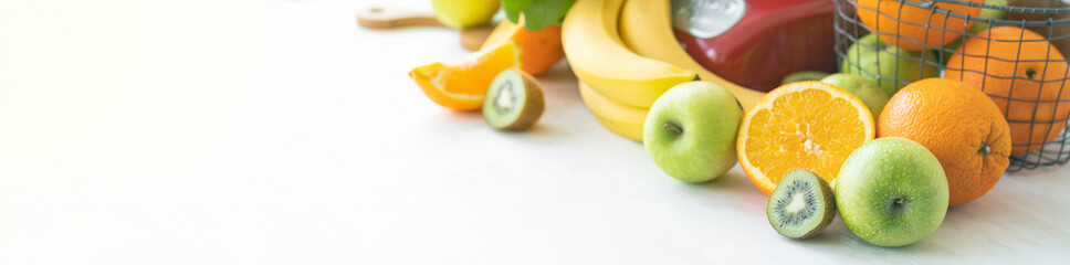 Young woman preparing homemade vitamin smoothie with apples, spinach, banana, kiwi, orange. Process of preparation healthy food. Concept of clean eating, dieting, low calories food. Banner copy space