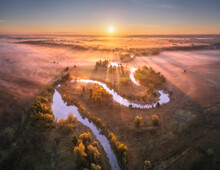 Aerial View Of Beautiful Curving River In Pink Low Clouds At Sunrise In Autumn In Ukraine. Turns Of River, Meadows, Grass And Orange Trees, Golden Sun Rays At Dawn In Fall. Top View Of River Coast