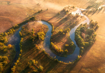 Wall Mural - aerial view of beautiful curving river in fog at sunrise in autumn in ukraine. turns of river, meado
