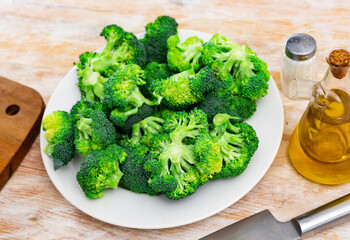 Wall Mural - Raw cut broccoli and olive oil on a cutting board. Top view