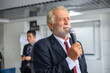 Elderly businessman holding a microphone speaking at a meeting