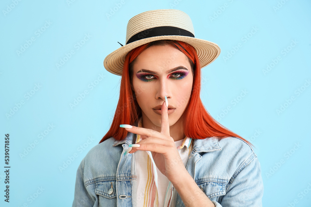 Stylish transgender woman showing silence gesture on blue background