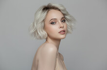 Portrait Of A Beautiful Blonde Girl With A Short Haircut. Gray Background.