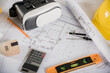 © sorapop - Architect workplace top view. Architectural blueprint paper project plans on desk table, tool for engineer contractor building design working drawing and VR glasses, industry virtual technology
