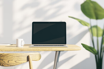 designer office desktop with empty laptop screen with mock up place in frame, concrete wall background with sunlight and shadows, blurry decorative plant and coffee cup. 3D Rendering.