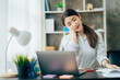 © Kritdanai - Portrait of smiling happy beautiful Asian woman relaxing using technology of laptop computer while sitting on table.Young creative girl working and typing on keyboard at cafe.work at home concept